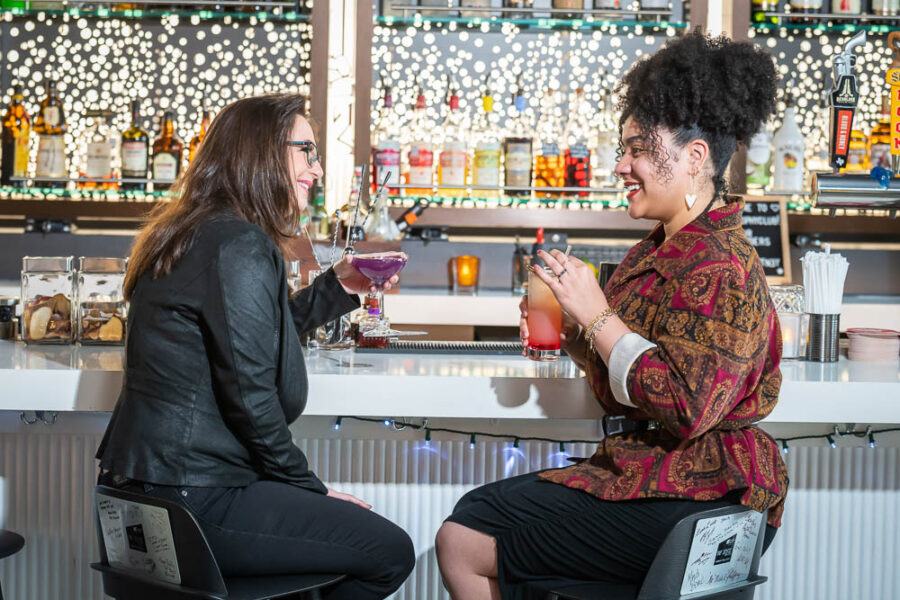 2 woman at bar w cocktails webres